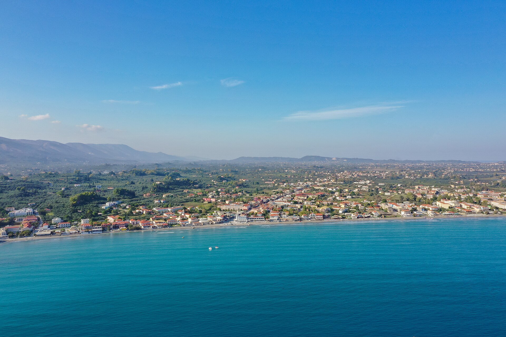 Luftbild der Bucht von Laganas mit türkisem Wasser, Sandstrand und Ort dahinter