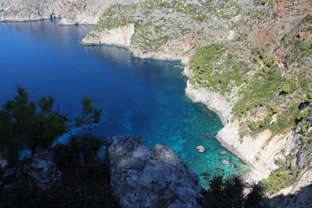 Blick von oben auf eine Bucht mit klarem Wasser zwischen bewachsenen Steilhängen bei Kambi