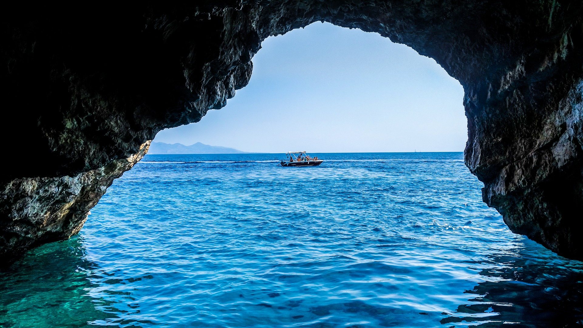 Blick aus einer Meereshöhle der Blue Caves auf das Ionische Meer mit einem Boot