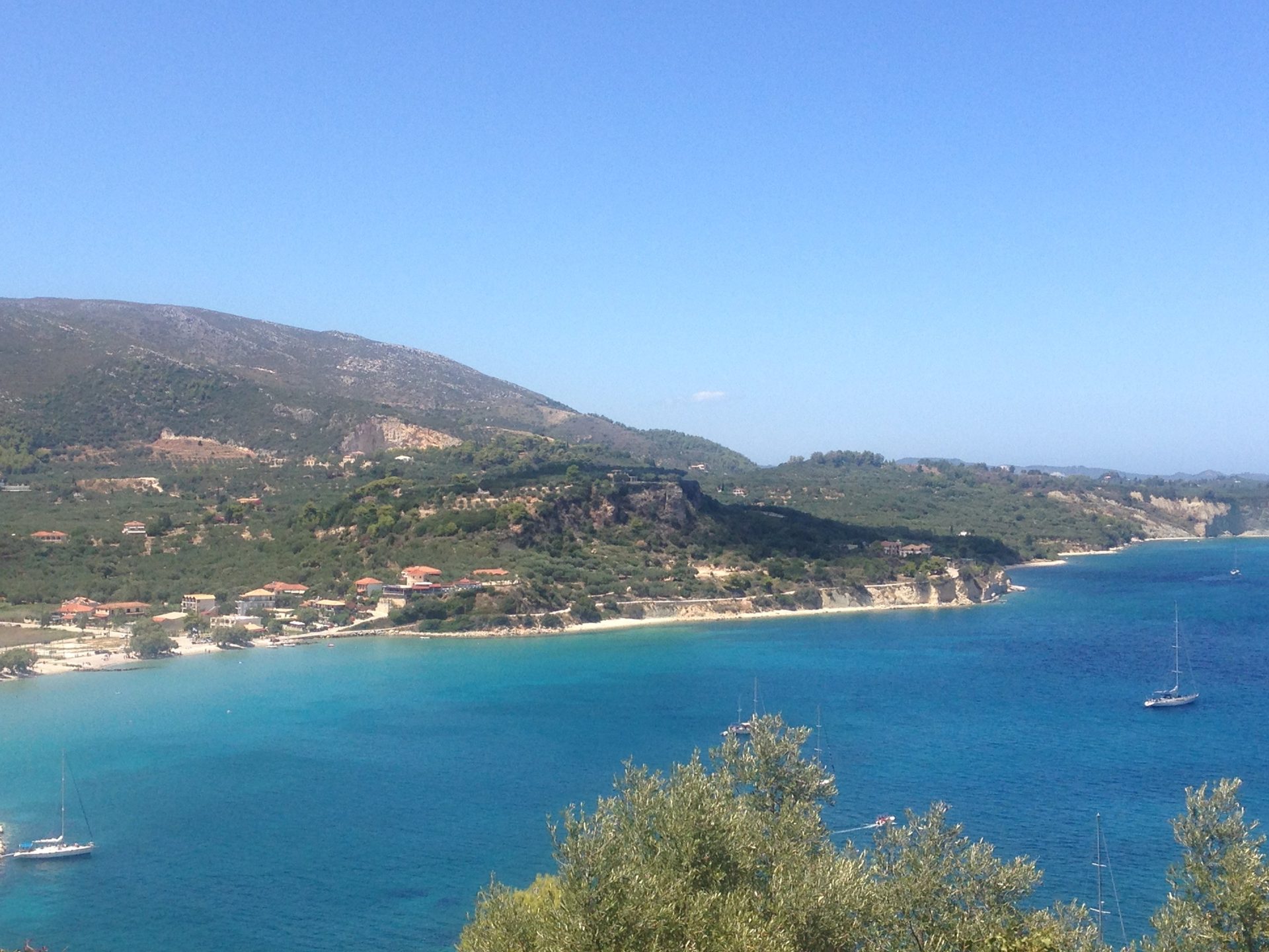 Bucht mit türkisem Wasser, grünen Hängen und Segelbooten