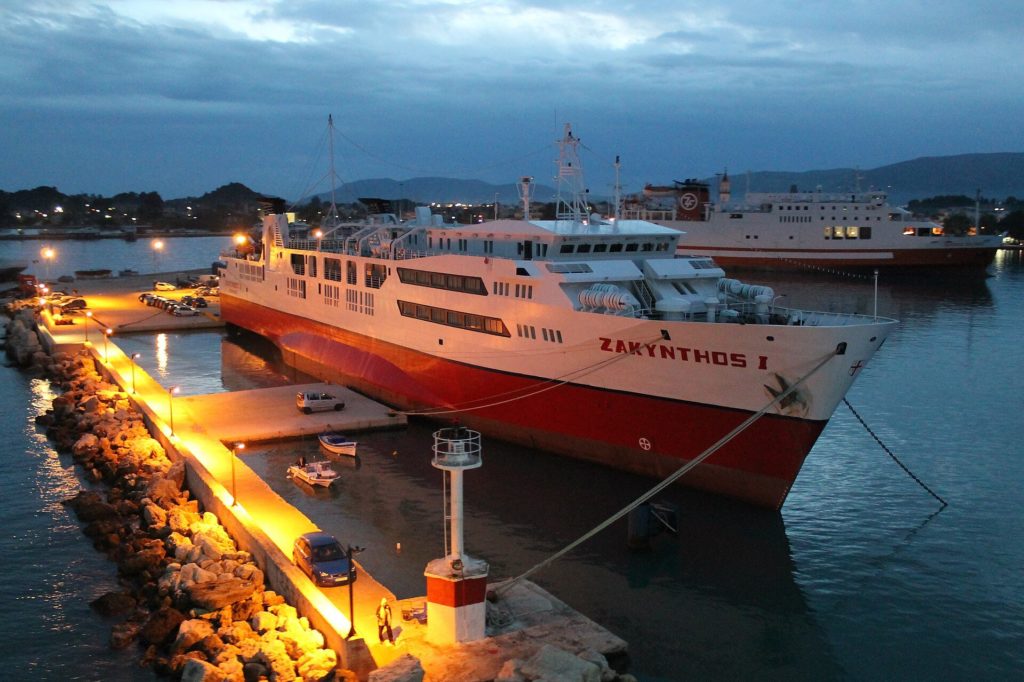 Rot-weiße Autofähre am beleuchteten Kai im Hafen von Zakynthos-Stadt in der Abenddämmerung