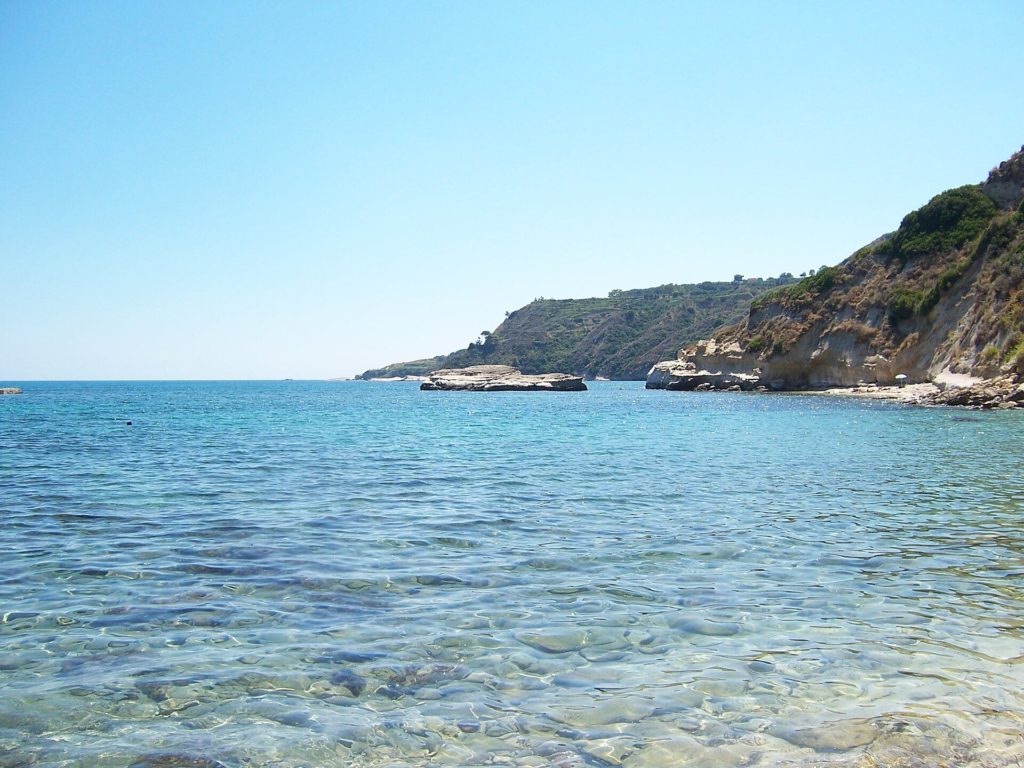 Klares, flaches Wasser vor einer felsigen Küste in der Bucht von Pessada