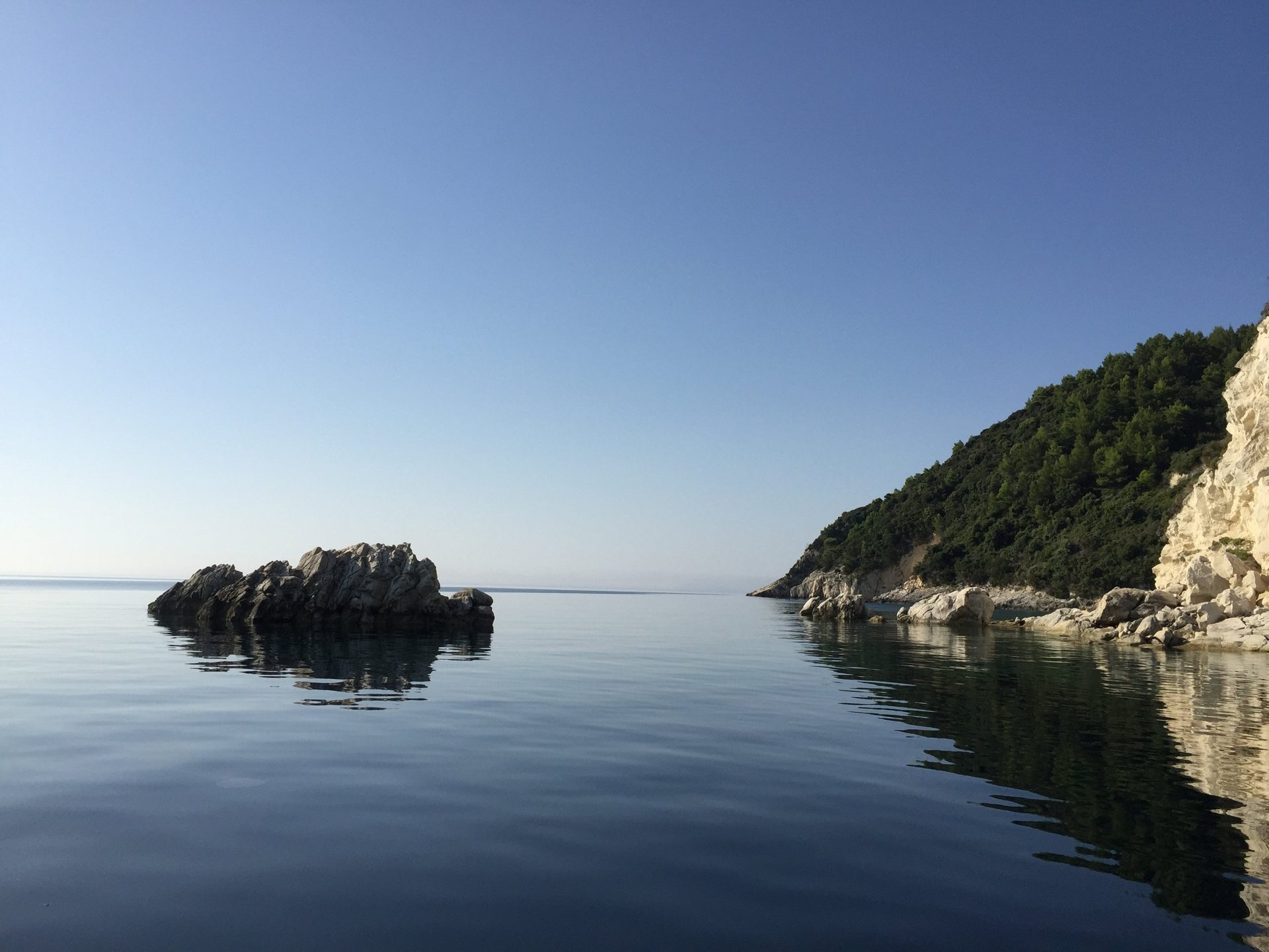 Ein Felsen im spiegelglatten Meer am Morgen