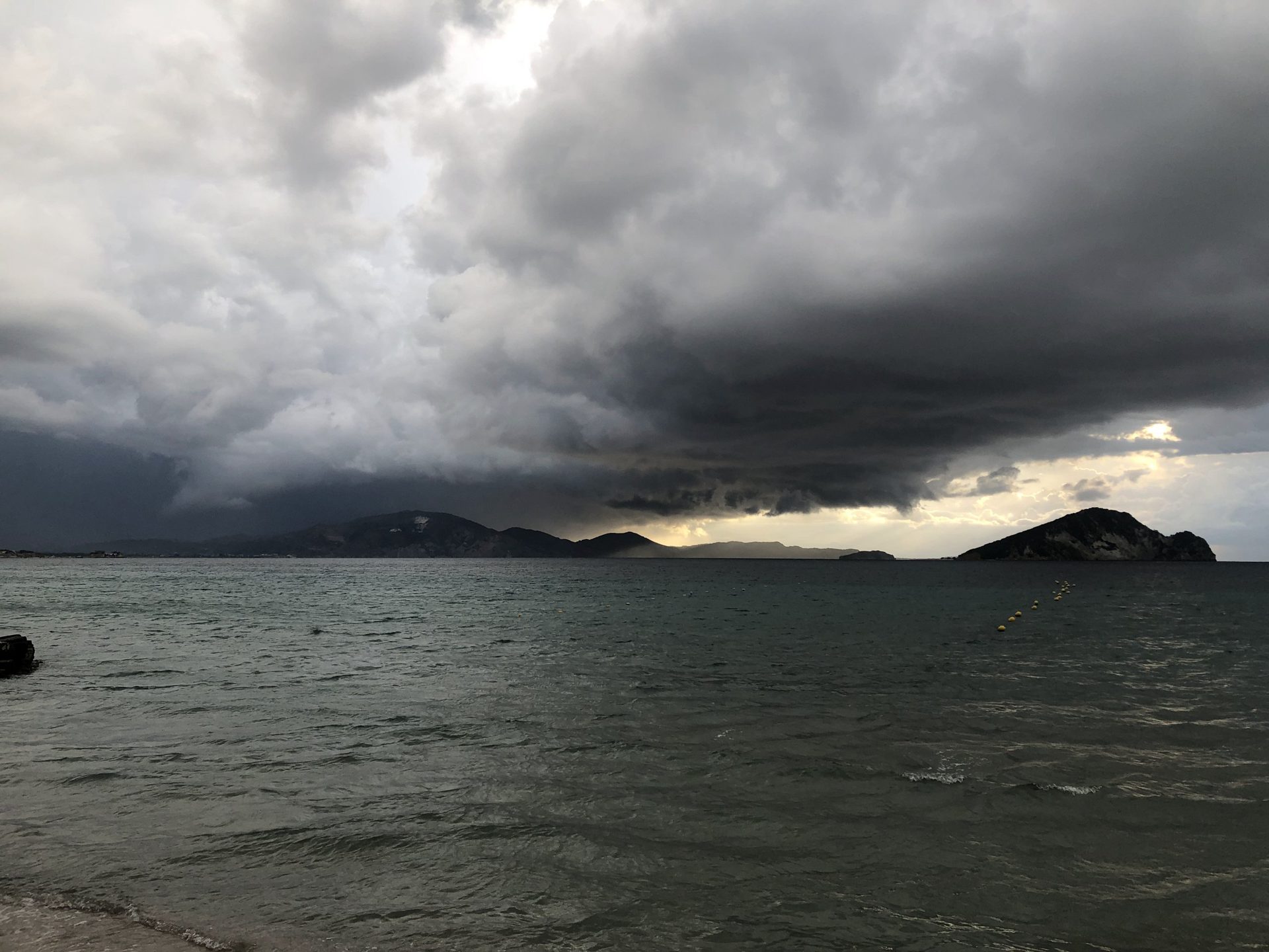 Dunkle Gewitterwolken über der Bucht von Laganas mit Marathonisi, September