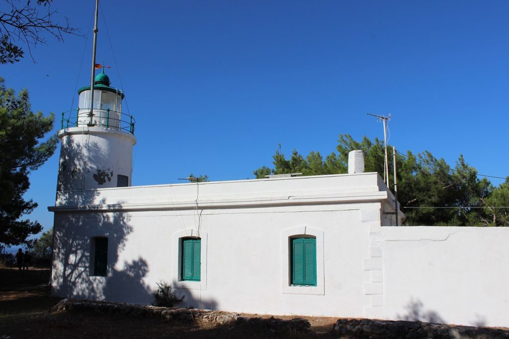 Weißer runder Leuchtturm mit grüner Laterne, angebaut an ein weißes Wärterhaus mit grünen Fensterläden