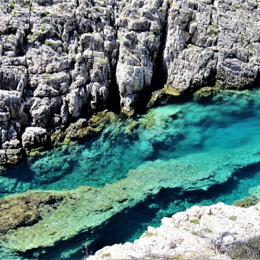 Türkisfarbenes Wasser in einer schmalen Felsrinne zwischen Kalkfelsen bei Korakonisi