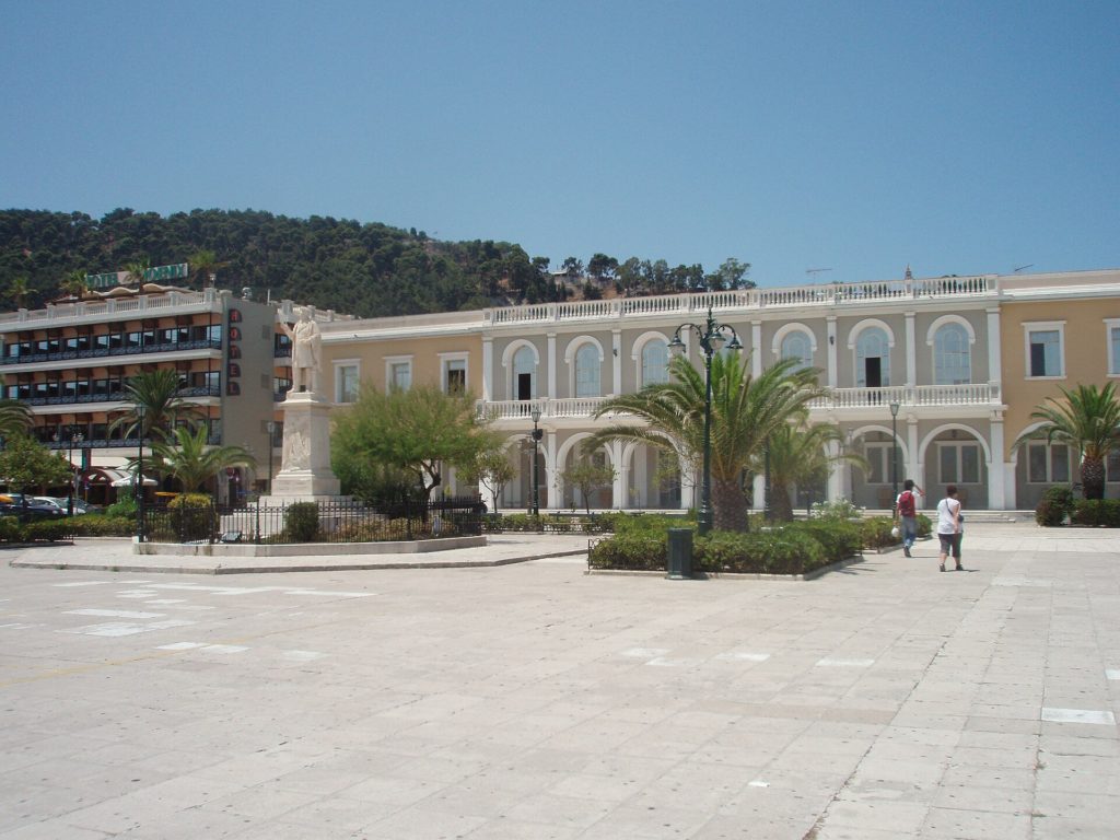 Weiter Solomos-Platz in Zakynthos-Stadt mit Palmen und hellen Gebäuden mit Arkaden