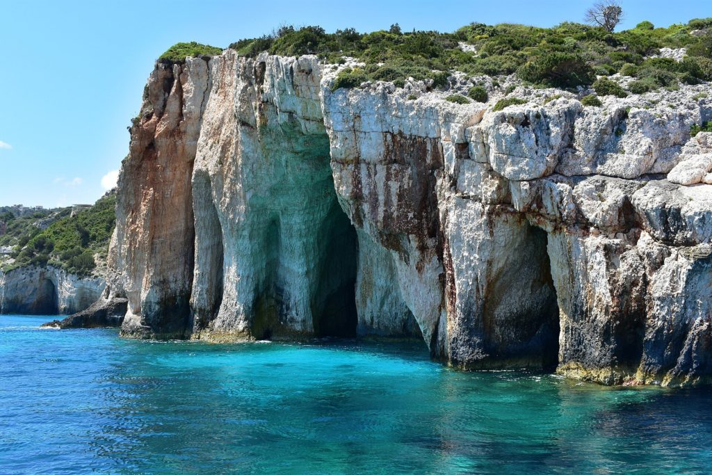 Weiße Kalkfelsen mit Höhlenbögen über türkisfarbenem Wasser an den Blue Caves