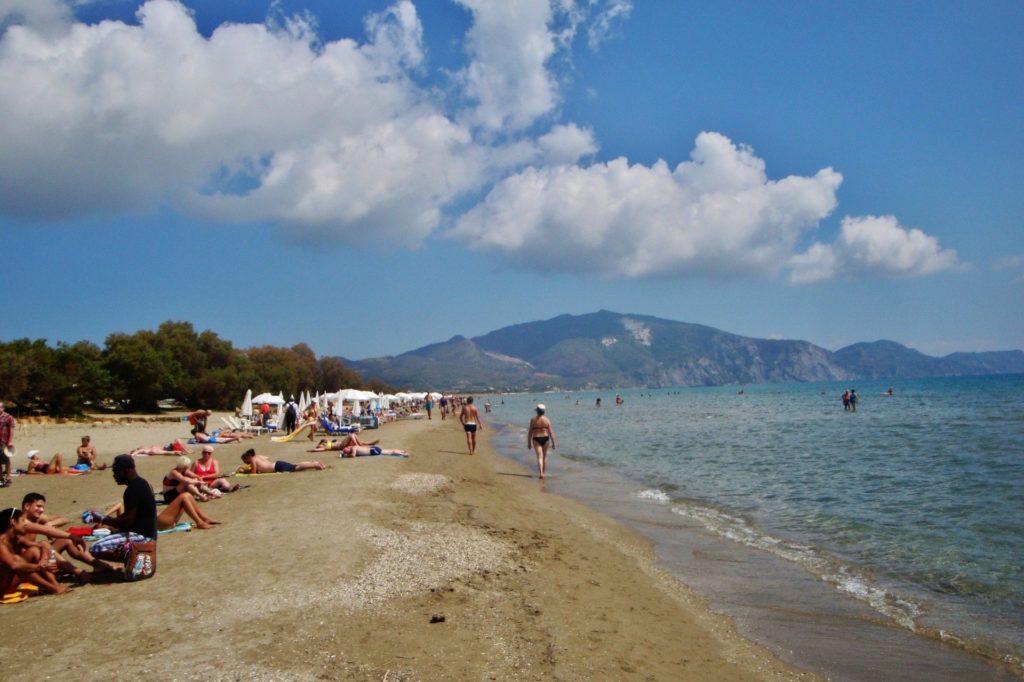 Sandstrand von Laganas mit Badegästen, im Hintergrund die Berge der Vasilikos-Halbinsel