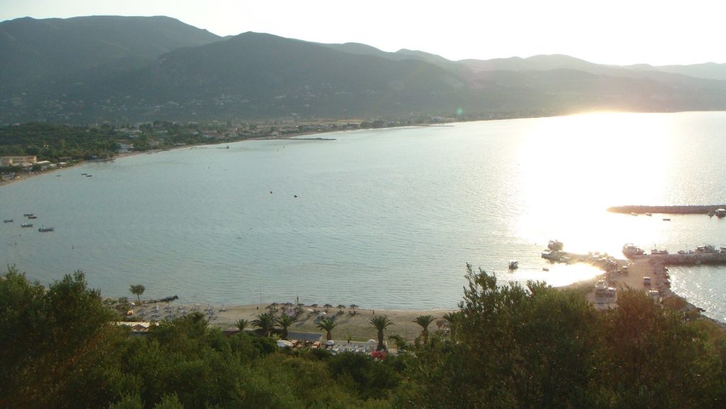 Blick von einem Hügel auf die Bucht von Alykes mit langem Sandstrand im Gegenlicht