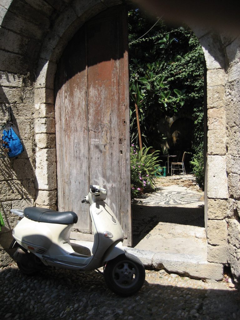 Motorroller vor einem Hoftor in einer griechischen Altstadt