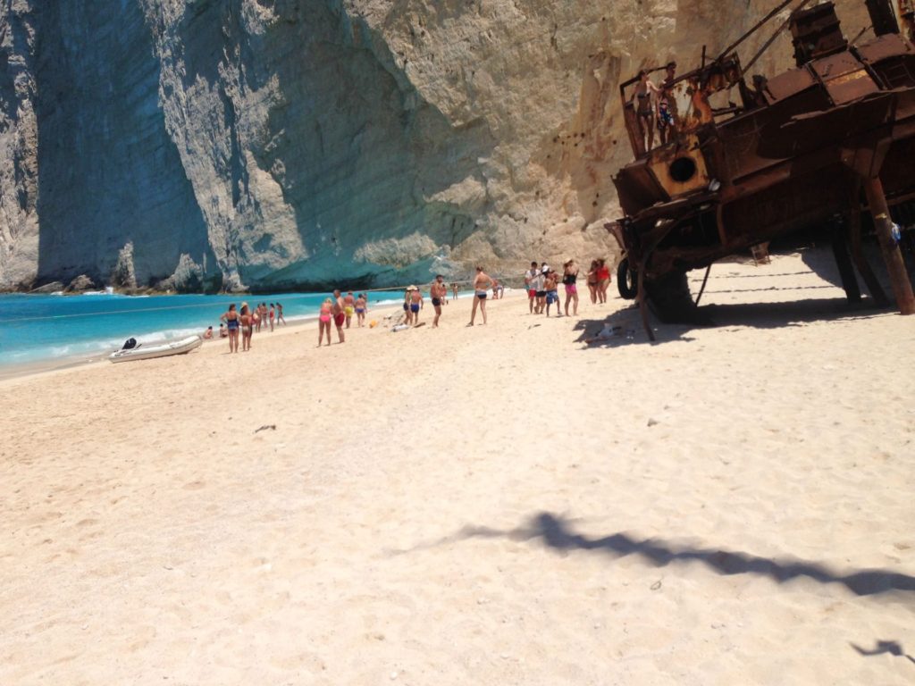 Das rostige Wrack der Panagiotis auf dem Strand von Navagio, dahinter Badegäste und die Steilwand