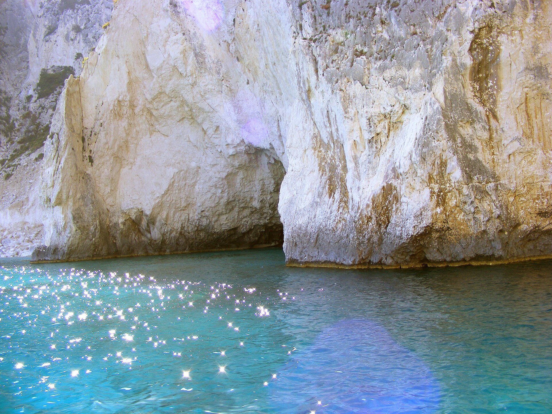 Helle Felswand mit Höhleneingängen über klarem, türkisfarbenem Wasser an der Küste von Keri auf Zakynthos