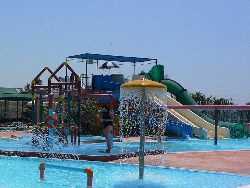 Flaches Becken mit Wasserpilzen, Spielturm und kleinen Rutschen