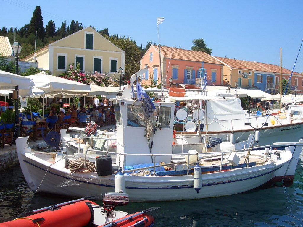 Fischerboote im Hafen von Fiskardo vor farbigen Häusern im Norden von Kefalonia