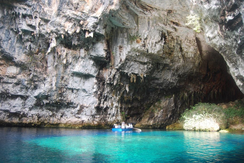 Türkisfarbenes Wasser im Höhlensee Melissani auf Kefalonia unter hellen Felswänden, darauf ein kleines Boot