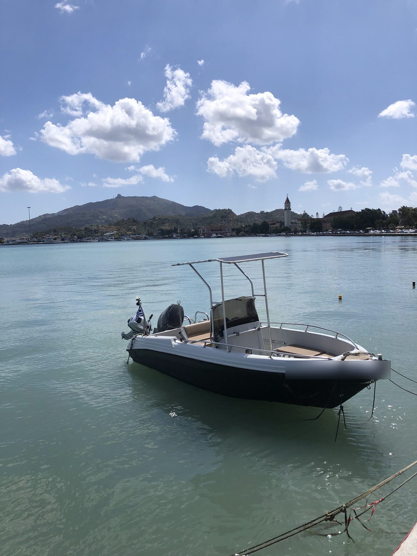 Ein Motorboot im Hafen von Zakynthos-Stadt, im Hintergrund der Glockenturm der Kirche Agios Dionysios und die Hügel über der Stadt